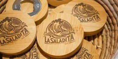 Wooden bottle opener with surfing pelican logo—Souvenirs section color photo.