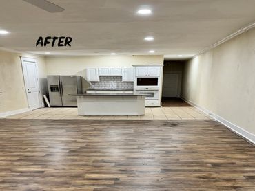 Renovated kitchen and living area with new flooring and modern appliances.