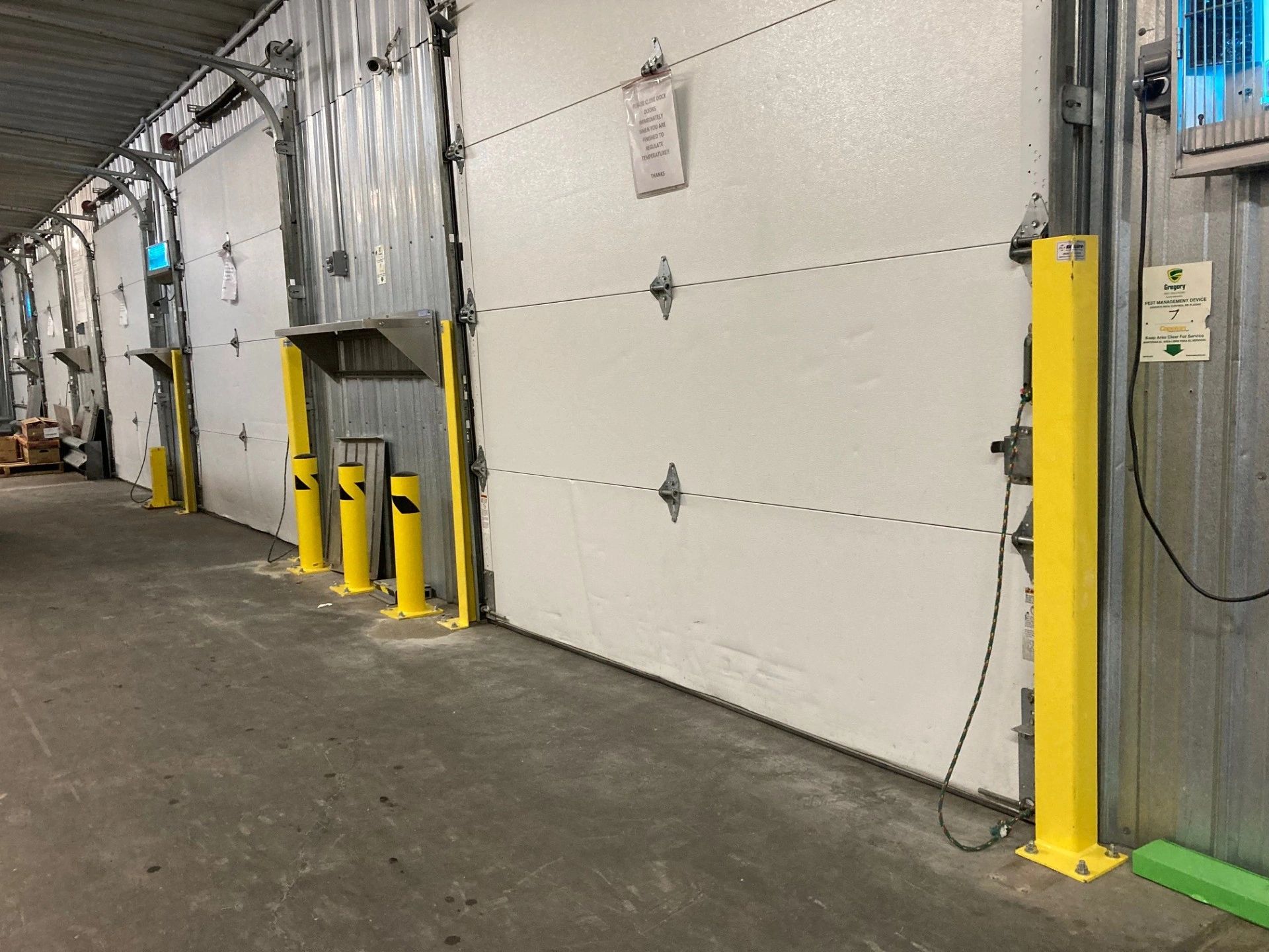 Industrial warehouse loading dock doors with yellow safety bollards.