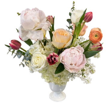 Elegant floral arrangement with roses, peonies, tulips, and greenery in a white vase.
