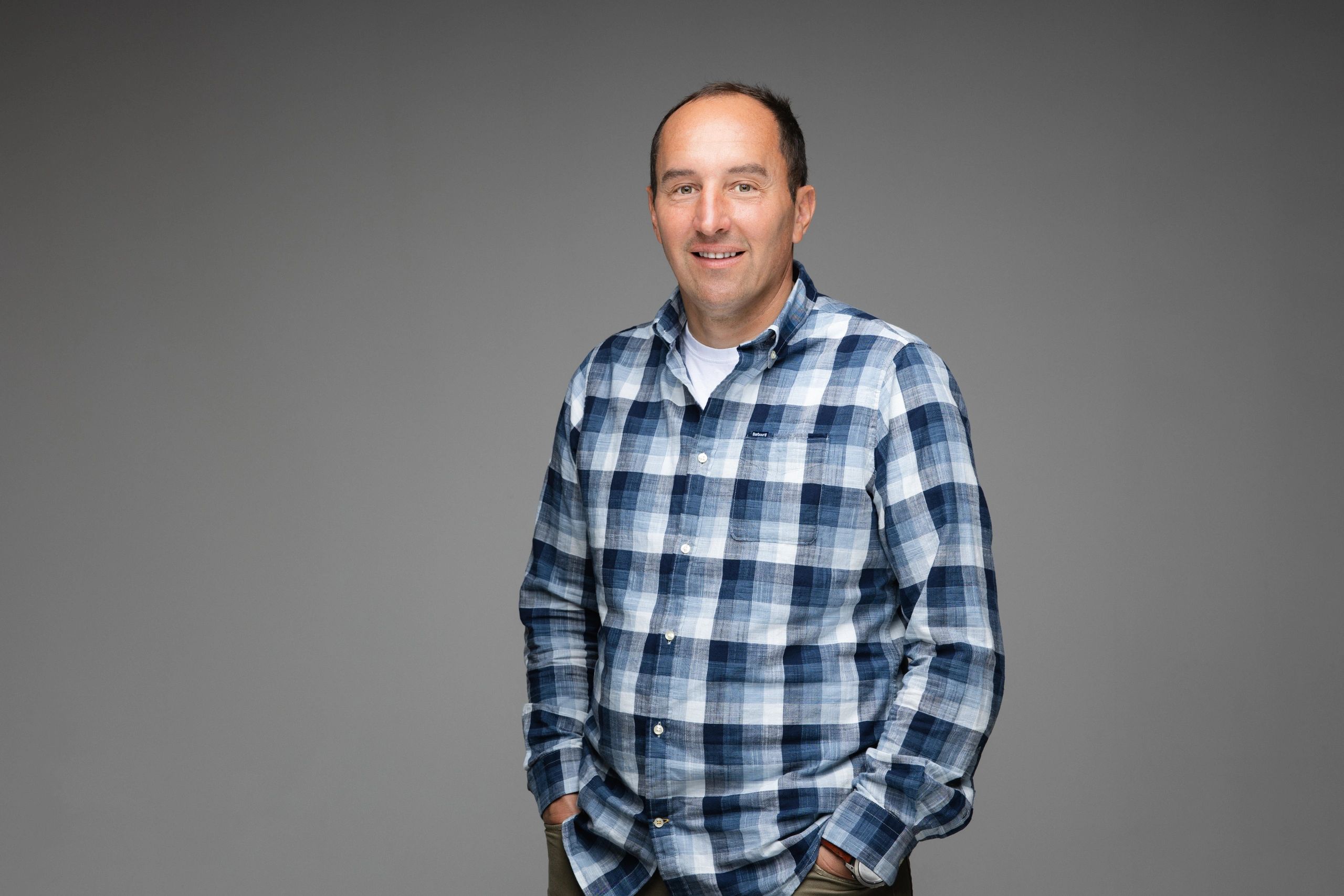 Man in blue plaid shirt smiling at the camera.