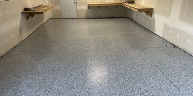 Clean, gray speckled garage floor with wooden shelves.
