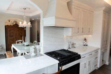 Elegant white kitchen with dining area and chandelier.