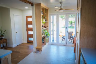Bright room with wooden shelves and glass doors leading outside.