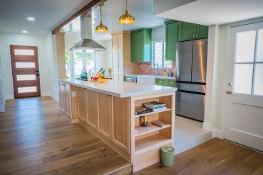 Modern kitchen with wooden floor and green cabinets.