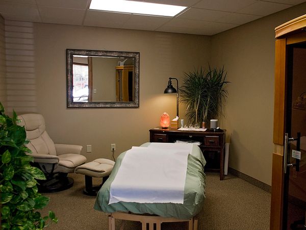 Cozy massage room with a treatment table and relaxing decor.