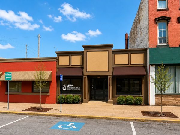 Facade of Allison Osteopathic Health clinic with adjacent buildings and parking.