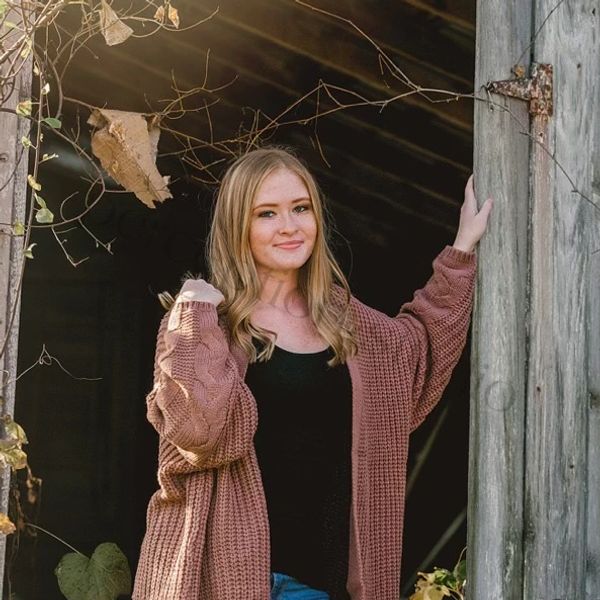 Young woman smiling, standing by an old wooden door.