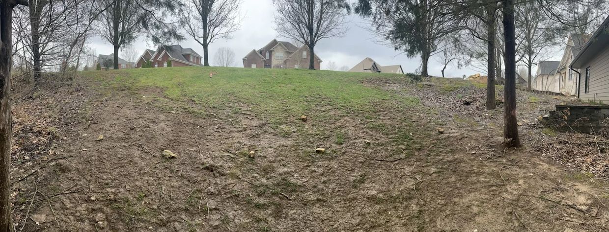 Eroding hillside with patchy grass and muddy soil.
