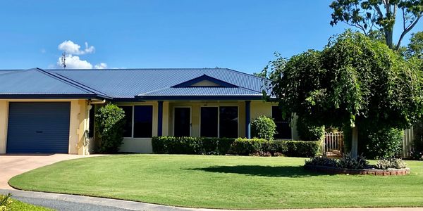 Single-story house with blue roof and well-maintained lawn on a sunny day.