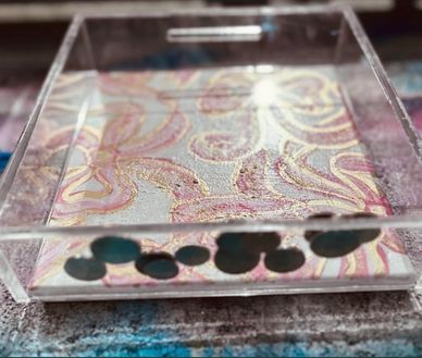 Transparent tray with artistic swirls and dark circular decorations.