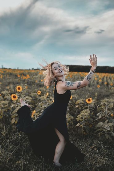 woman running through field of sunflowers. Happiness is a practice, a goal, and a result.