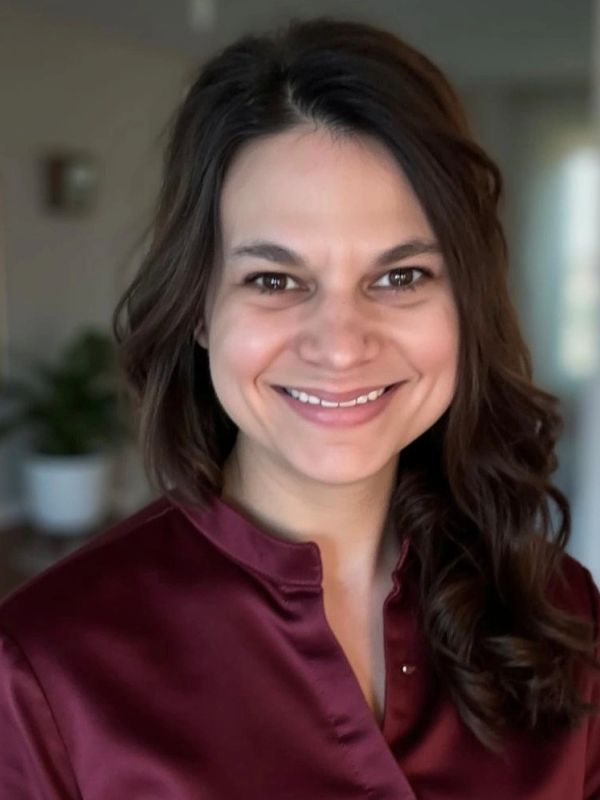Smiling woman with brown hair in maroon blouse.