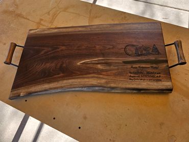 A black walnut cutting board featuring sturdy, easy-to-grip handles.