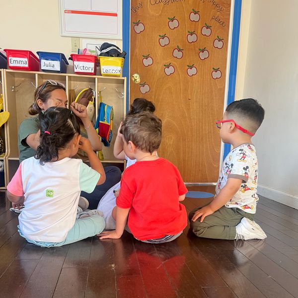 Teacher interacting with young children in a classroom setting.