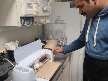 A person pressing a button on a die-cutting machine.