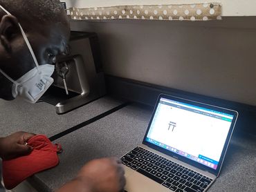 A person with a mask on his face using a computer.