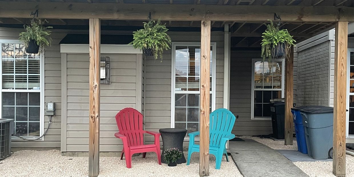 Two colorful chairs and plants under a wooden patio.