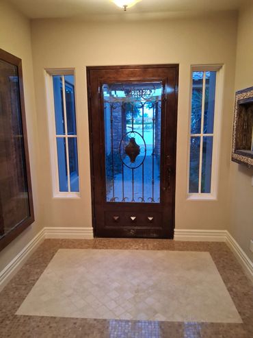 Entryway with textured painted walls, a wood front door and decorative tile flooring.