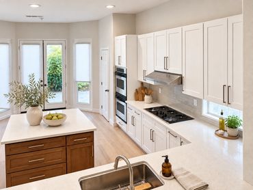 La Quinta kitchen with white cabinets, wood-tone island and new countertops. Decor virtually staged.