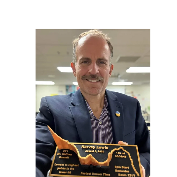 Man proudly holding a plaque commemorating a hiking achievement.