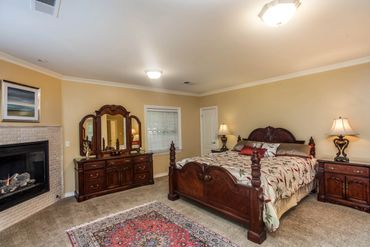 Classic bedroom with wooden furniture, a fireplace, and a patterned rug.