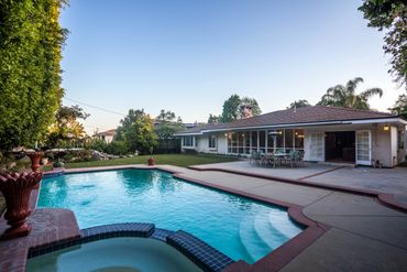 Spacious backyard with a swimming pool and patio dining area.