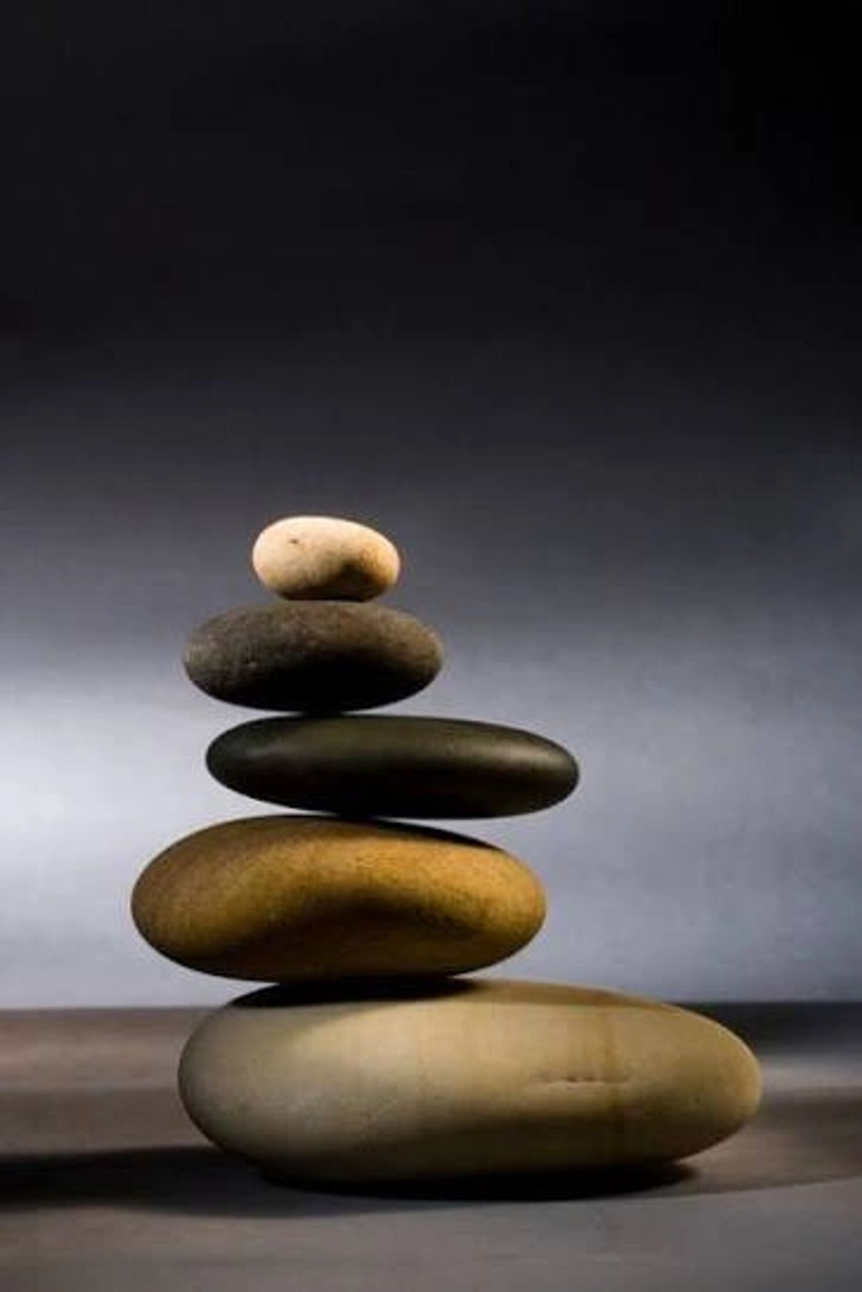 A stack of five smooth stones balanced in ascending size order against a gradient background.
