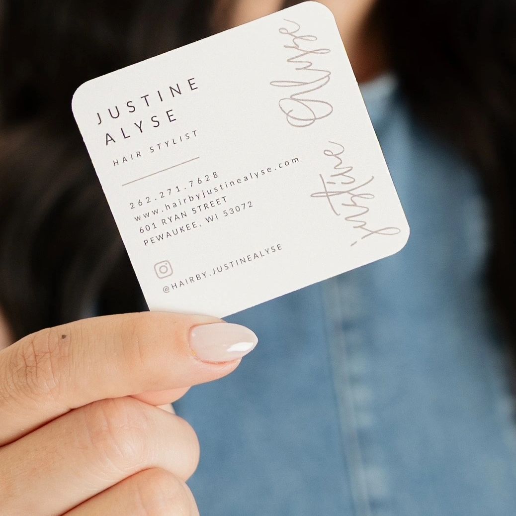 Hand holding a hairstylist business card.