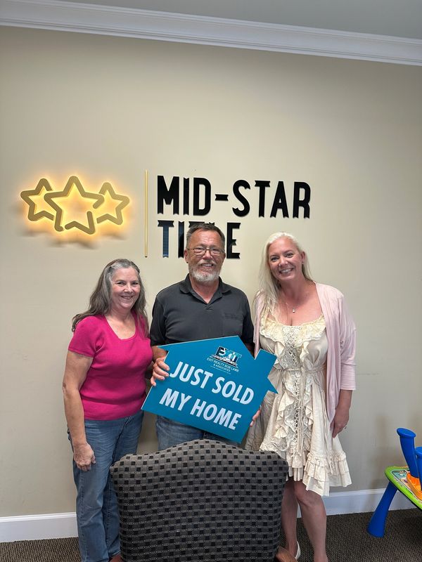 Happy buyers with sold sign.