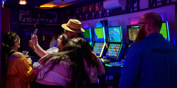 Group of people taking a selfie in a casino with a security guard nearby.