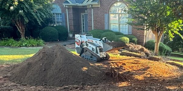This is an image of a Bobcat MT100 mini skid steer owned by Mini Skiddi Services spreading top soil.