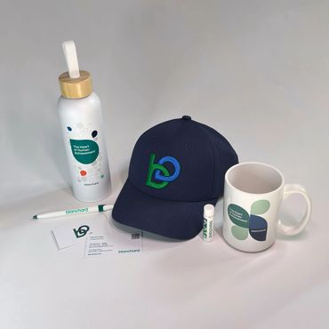 Branded items including a cap, mug, water bottle, pen, lip balm, and business cards.