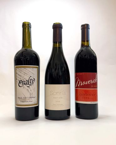 Three vintage wine bottles with distinct labels and years.