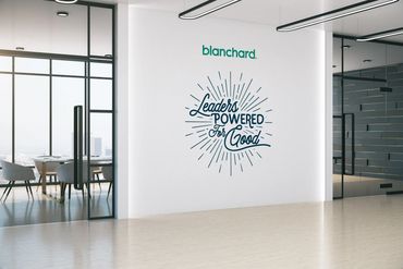 Modern office space with motivational wall art saying "Leaders Powered For Good."