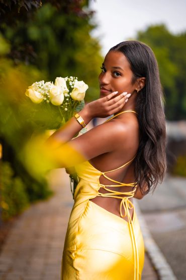 Woman in a yellow dress holding white roses outdoors.for a prom session. NYC Graduation & Prom Photographer | Taisha Marie Photos