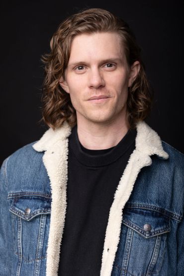Portrait of a man with curly hair wearing a denim jacket.NYC Headshot & Branding Photographer | Taisha Marie Photos