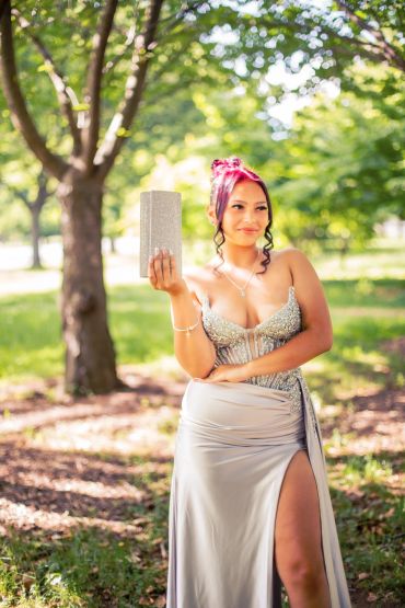 Woman in a silver gown holding a glittery clutch outdoors. NYC Graduation & Prom Photographer | Taisha Marie Photos