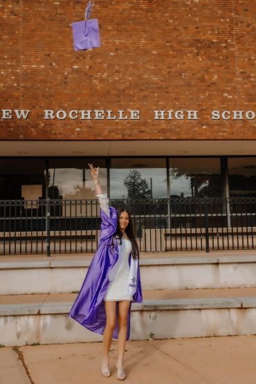 Graduate throws cap joyfully outside high school. NYC Graduation & Prom Photographer | Taisha Marie Photos