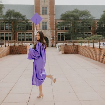Graduate in purple gown celebrates outside a historic clock tower building.NYC Photography Pricing | Taisha Marie Photos
