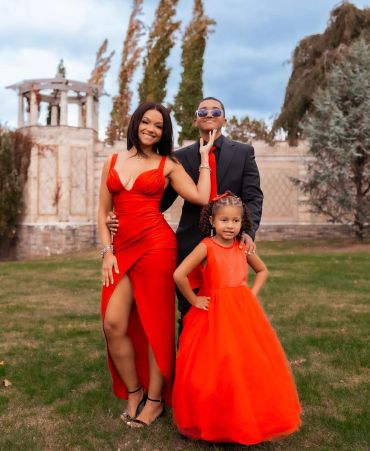 Family dressed elegantly in red and black outdoors.