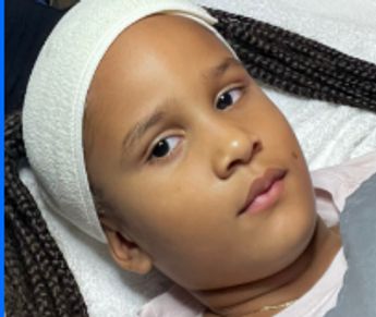 Young child with a white headband lying down, receiving a gentle Mini Facial/Kids treatment.