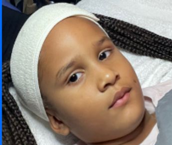 Young child with a white headband lying down, receiving a gentle Mini Facial/Kids treatment.