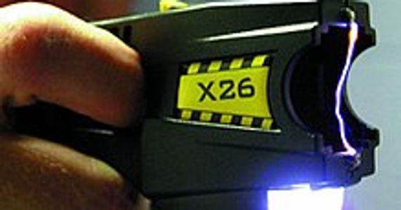 A Taser-brand stun gun with cartridge removed, making an electric arc between its two electrodes.