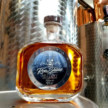 Bottle of Roo Shine Mutiny Spiced Rum in a distillery setting.