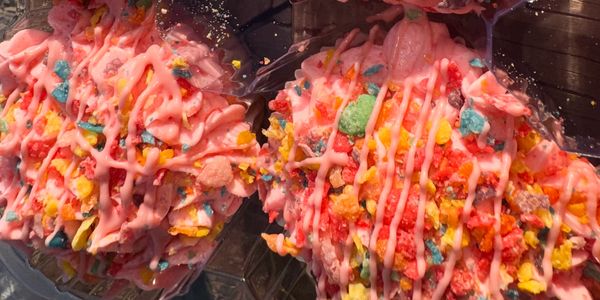 Colorful dessert with pink drizzle and fruity cereal topping.