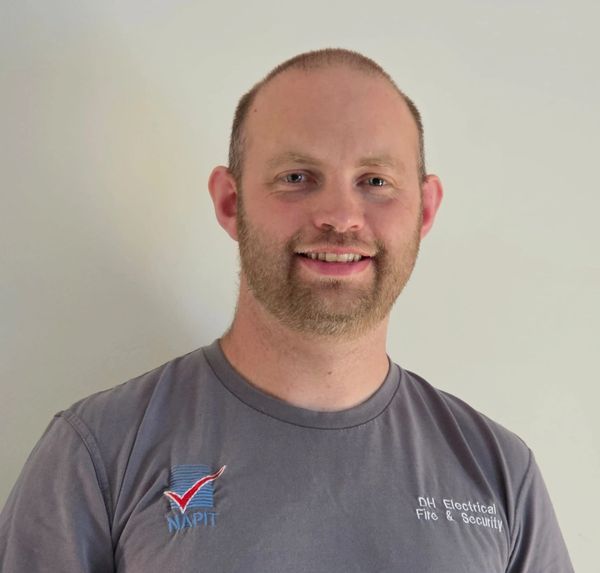 Smiling man in a grey NAPIT DH Electrical Fire & Security t-shirt.