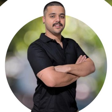 Man in black shirt and beige cargo shorts standing with arms crossed.