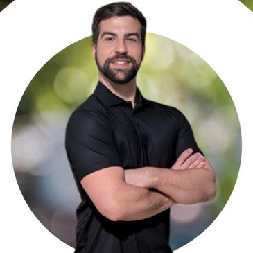 Confident man with crossed arms standing against a blurred green background with a white circular design.
