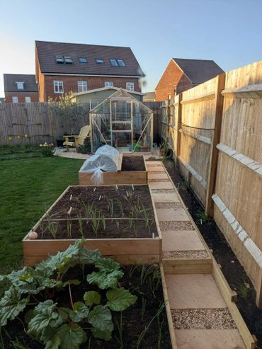 Well-maintained backyard garden with raised beds and a greenhouse.